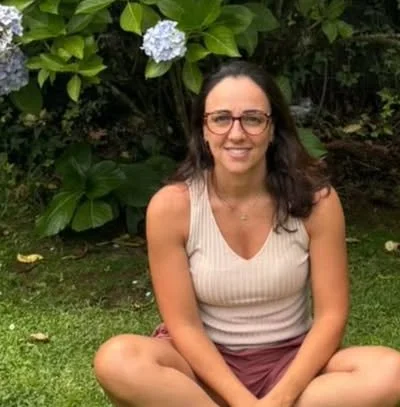 Mariana Freire sentada em um jardim com hortênsias